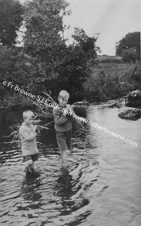 BOYS WADING THROUGH STREAM